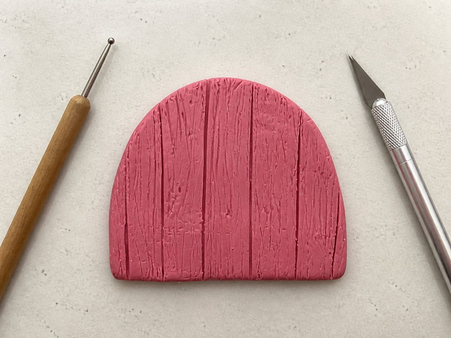 Rosa Grundform einer Wichteltür aus FIMO mit eingeritzter Holzstruktur